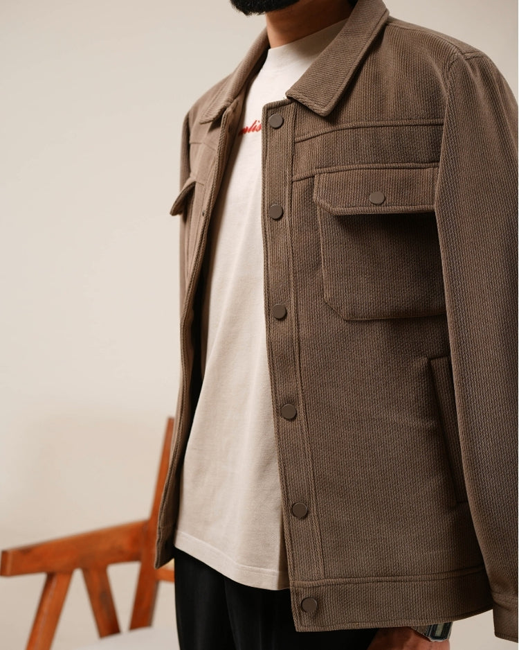 Person wearing a brown corduroy jacket over a white shirt with a blurred background