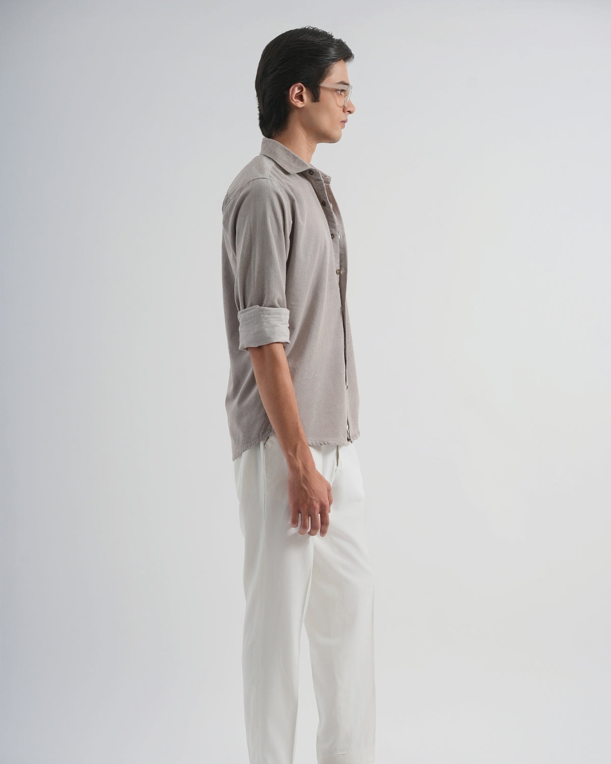 Man wearing a light gray shirt and white pants on a plain background