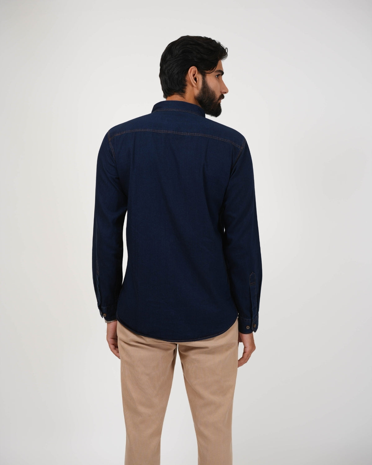 Man wearing a navy shirt and beige pants on a white background