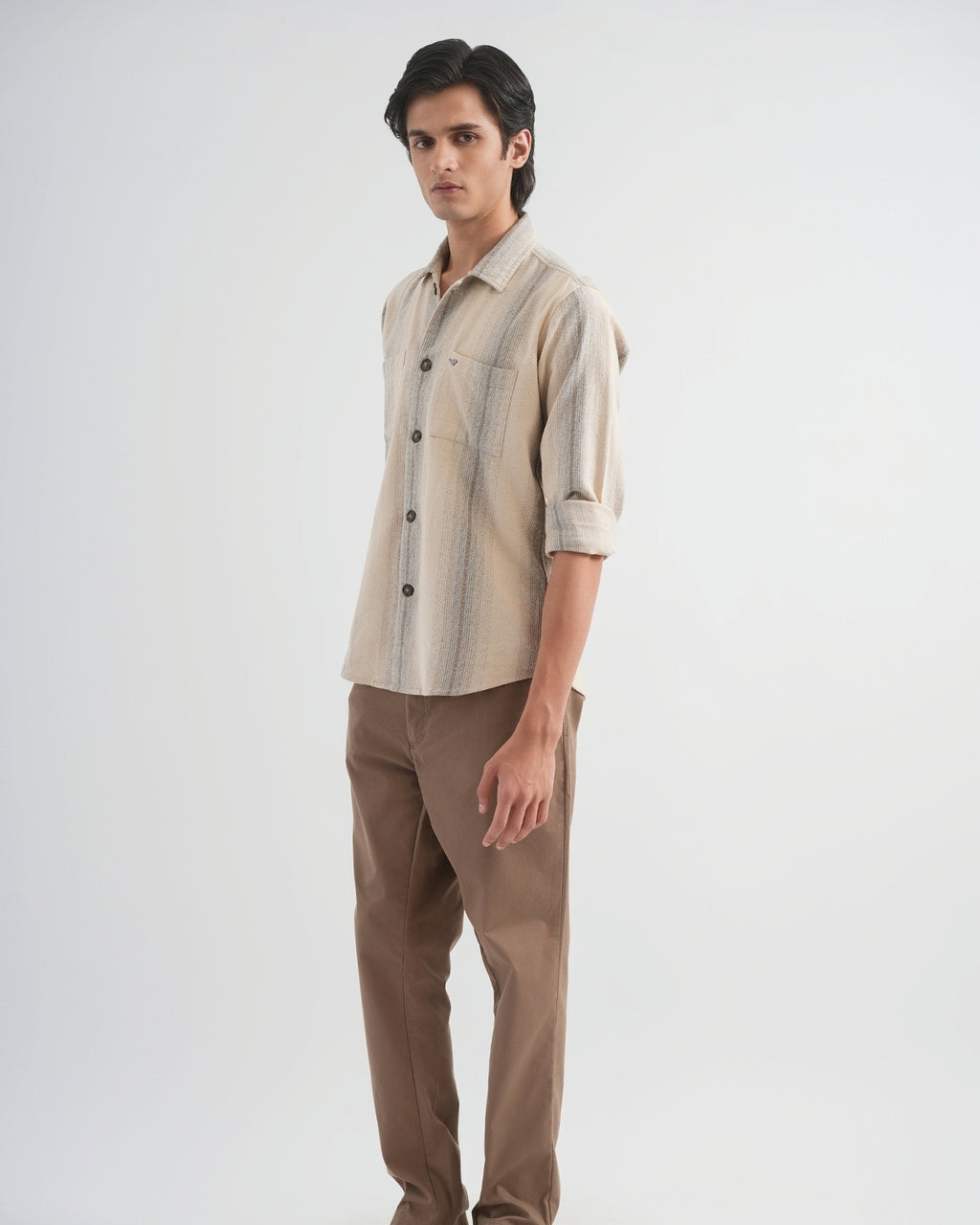 Man wearing a beige and brown striped shirt with brown pants on a white background