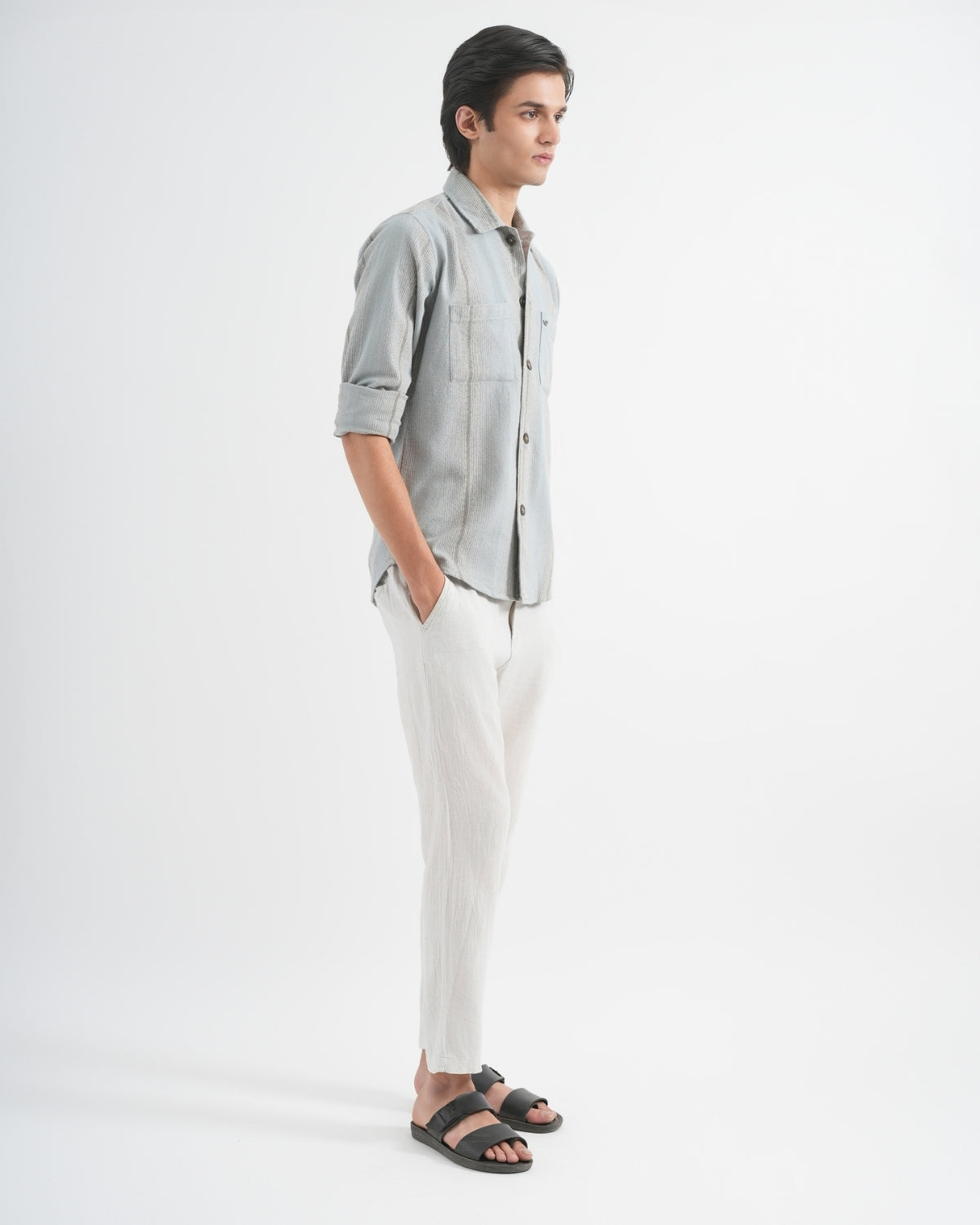 Man wearing a light gray shirt and white pants on a white background