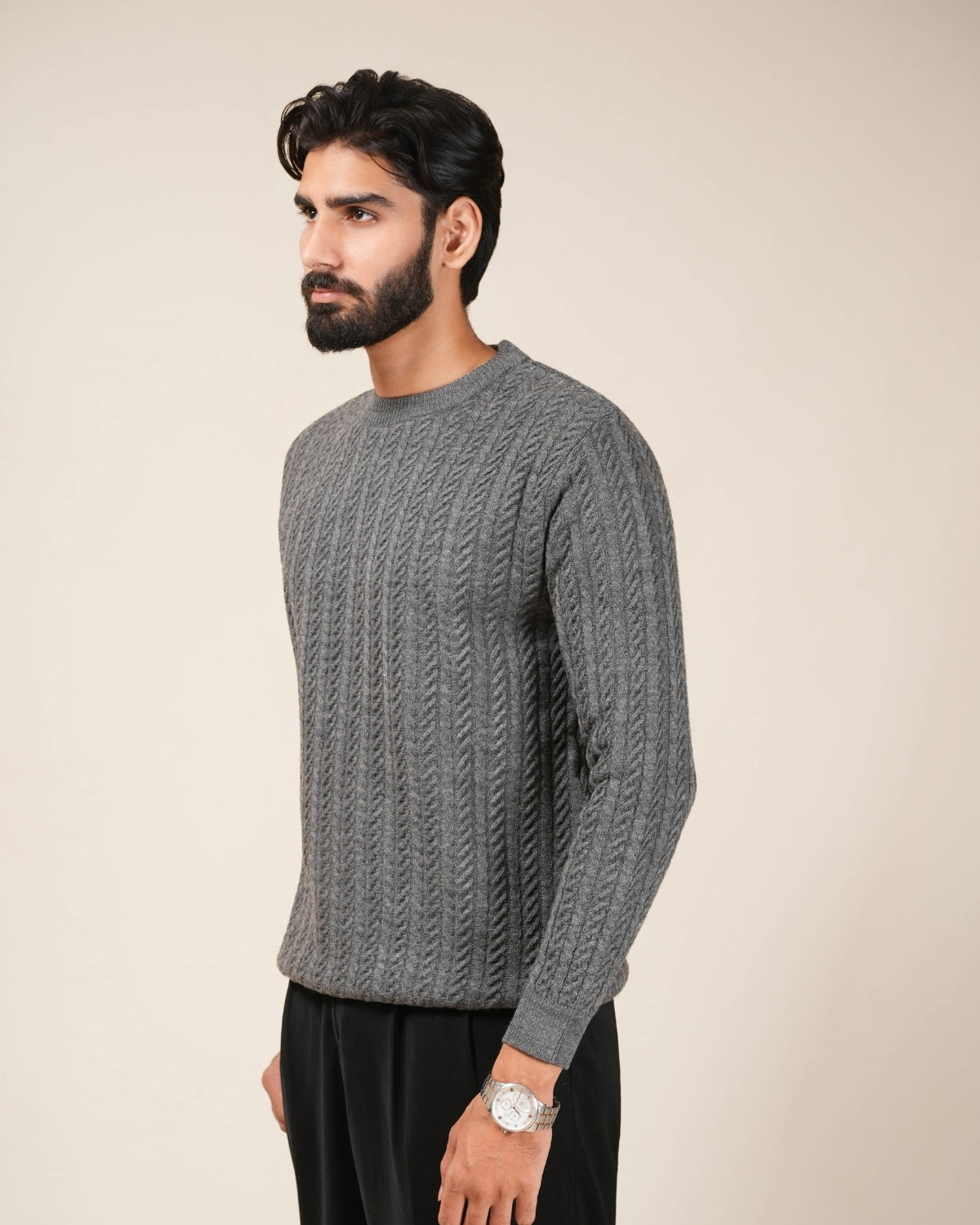Man wearing a gray cable knit sweater against a beige background