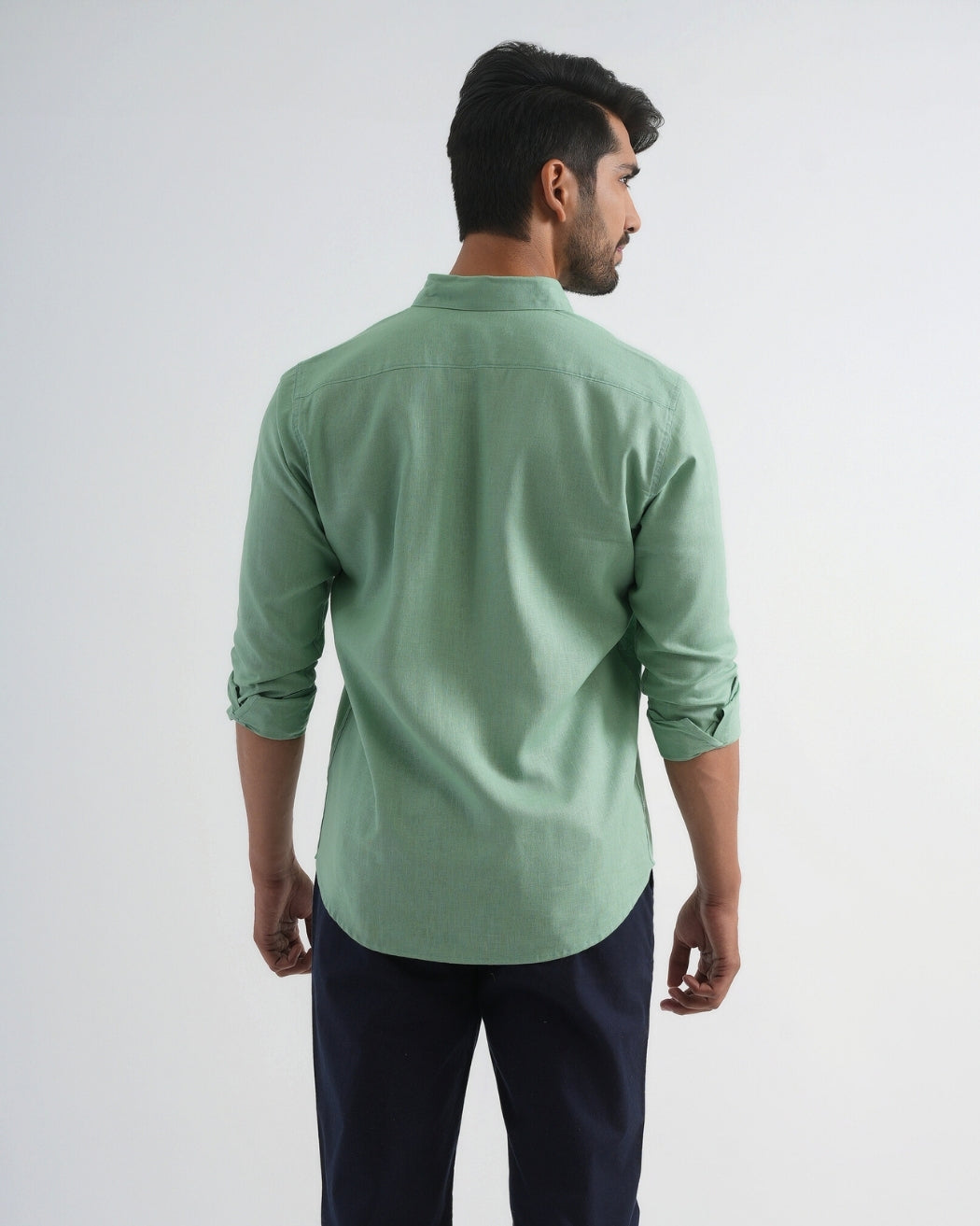 Man wearing a light green shirt and dark pants on a white background