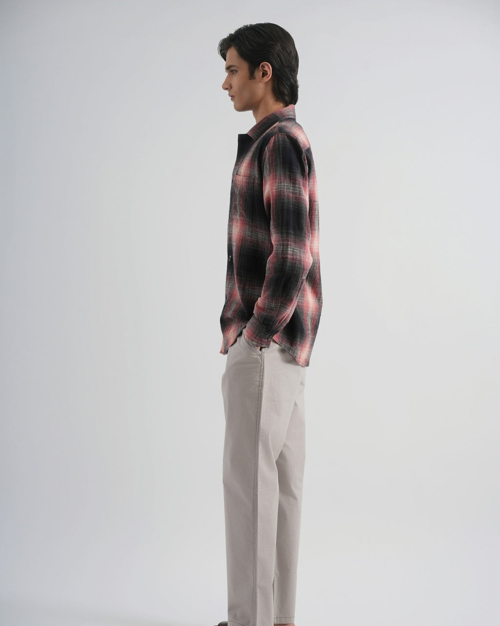 Man wearing a plaid shirt and light-colored pants on a white background