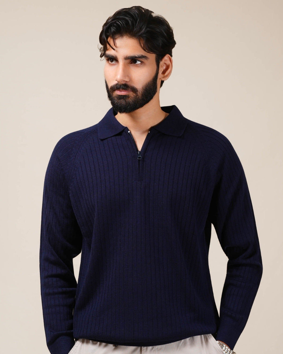 Man wearing a navy blue sweater against a beige background