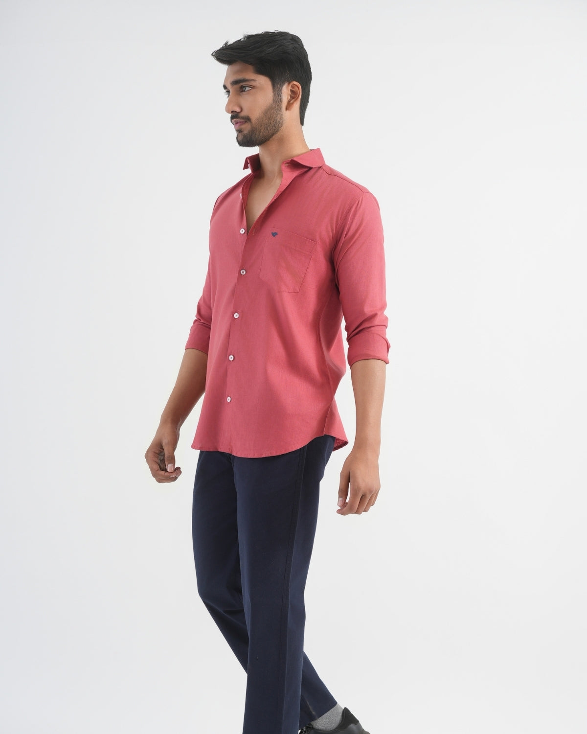 Man wearing a red shirt and dark pants on a white background