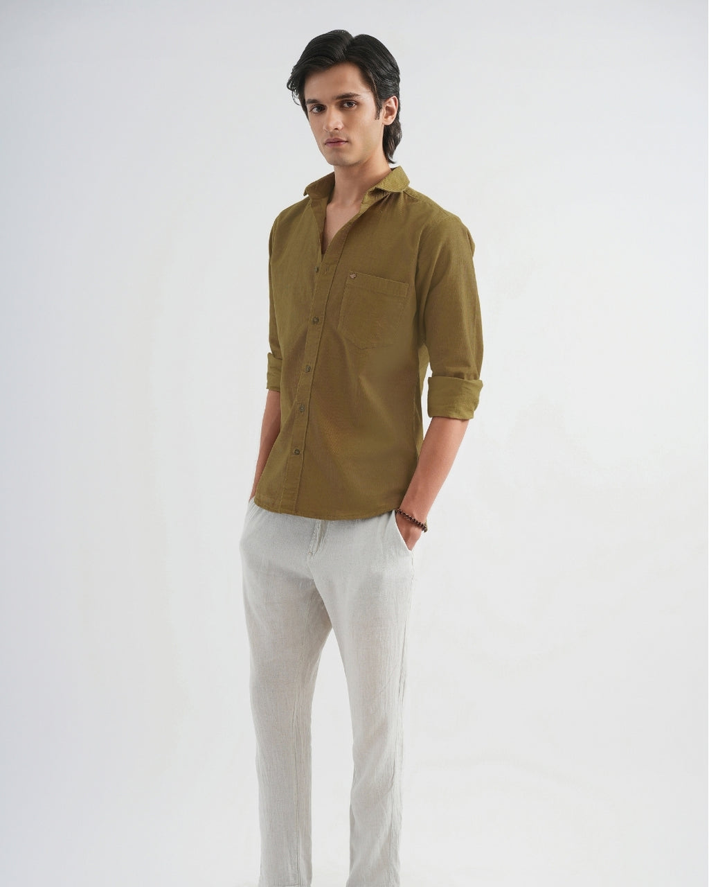 Man wearing a brown shirt and light gray pants on a white background