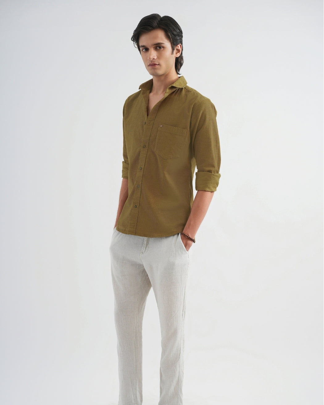 Man wearing a brown shirt and light gray pants on a white background