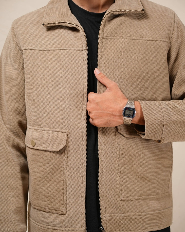 Person wearing a beige jacket with a neutral background