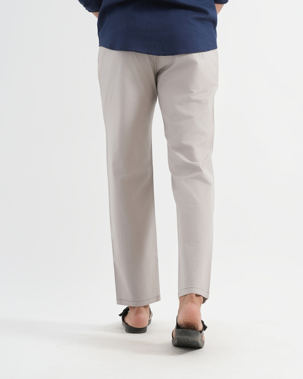 Person wearing light gray pants and a navy top on a white background