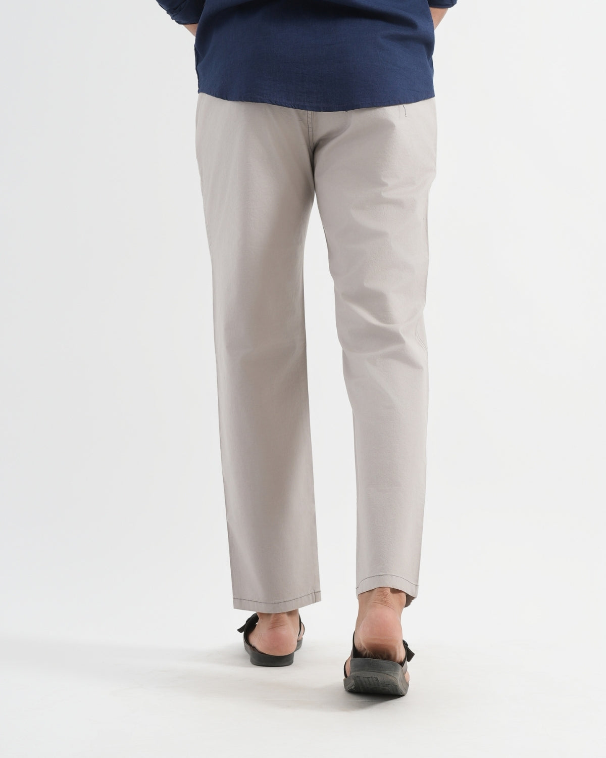 Person wearing light gray pants and a navy top on a white background