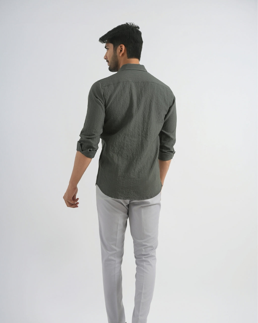Man wearing a dark green shirt and light gray pants on a white background