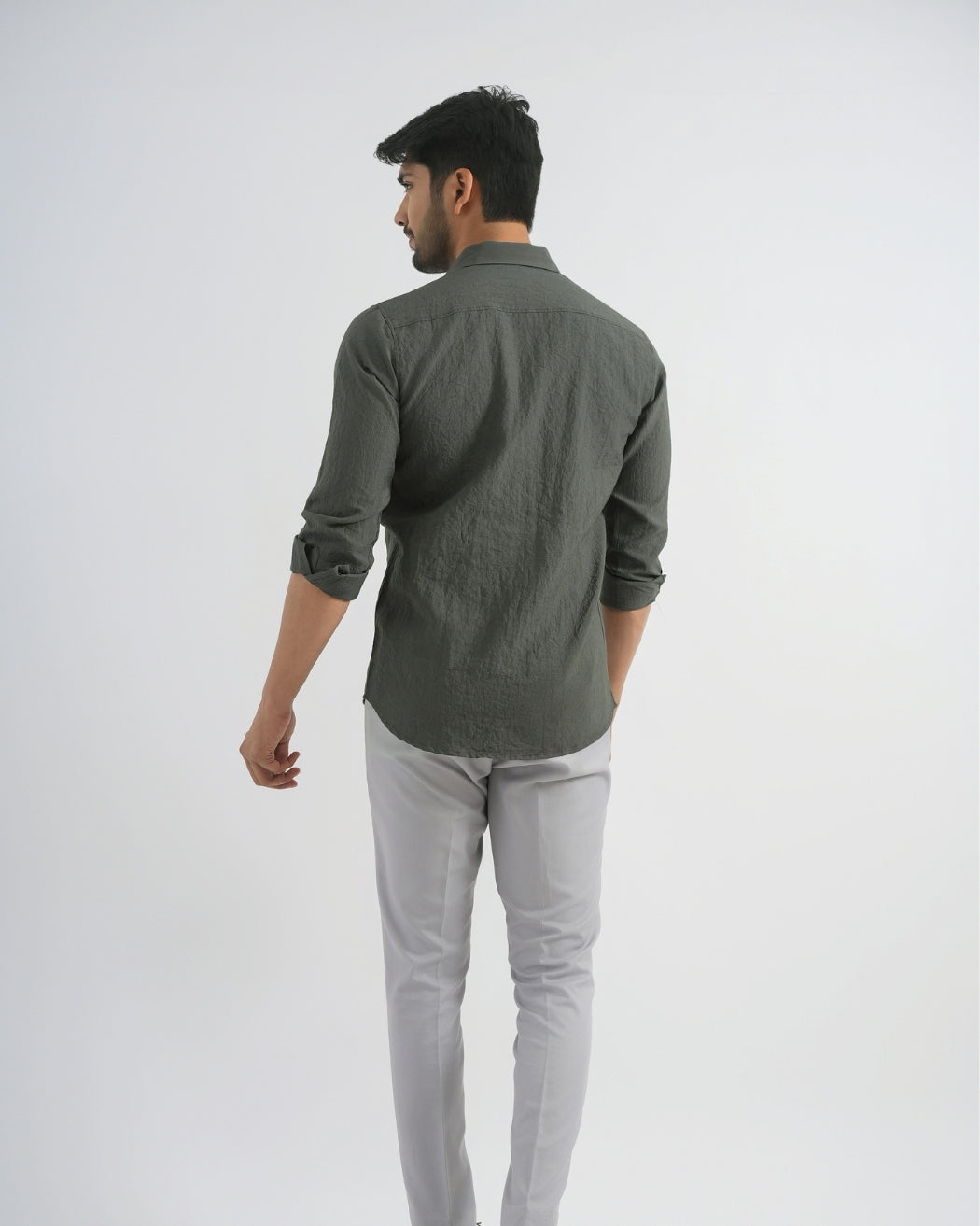 Man wearing a dark green shirt and light gray pants on a white background