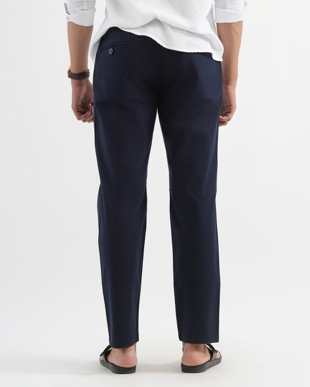 Person wearing navy pants and a white shirt on a white background