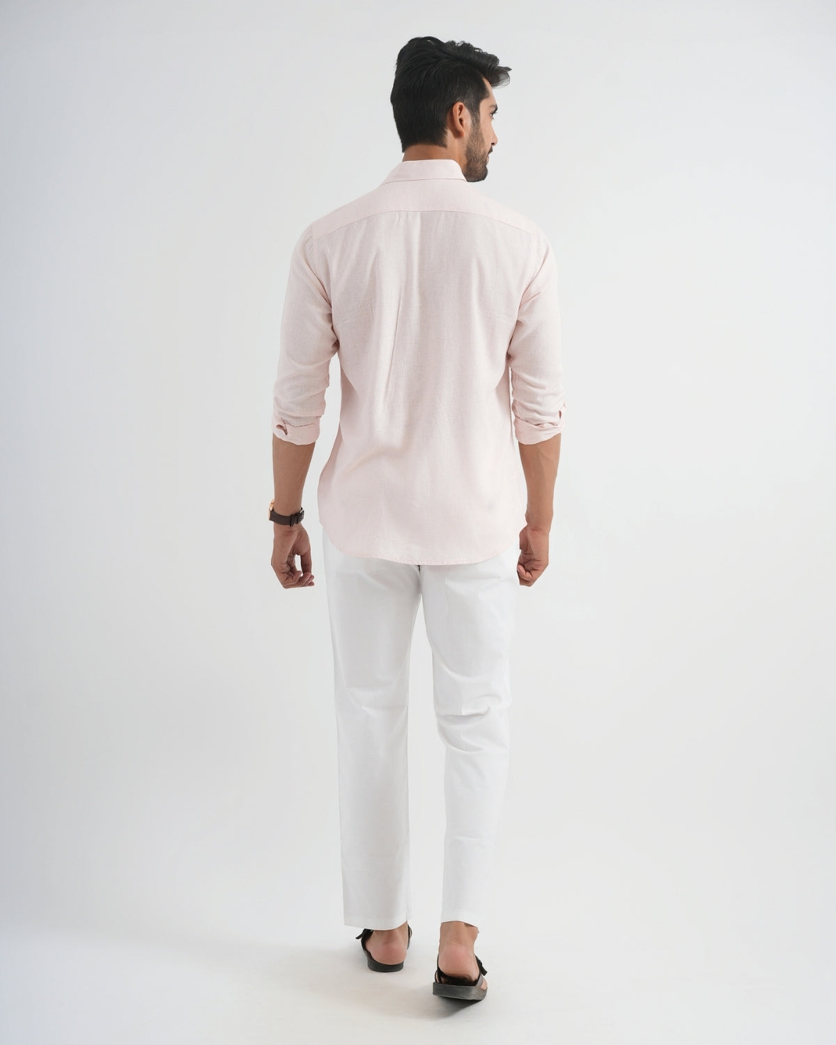 Man wearing a light pink shirt and white pants on a white background