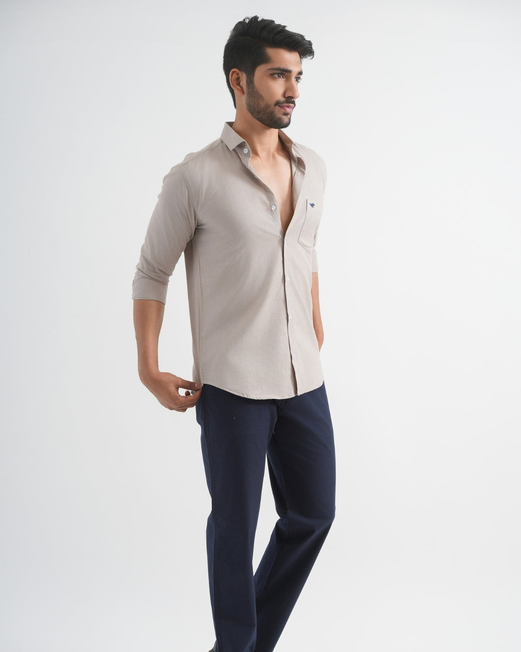 Man wearing a beige shirt and navy pants on a white background