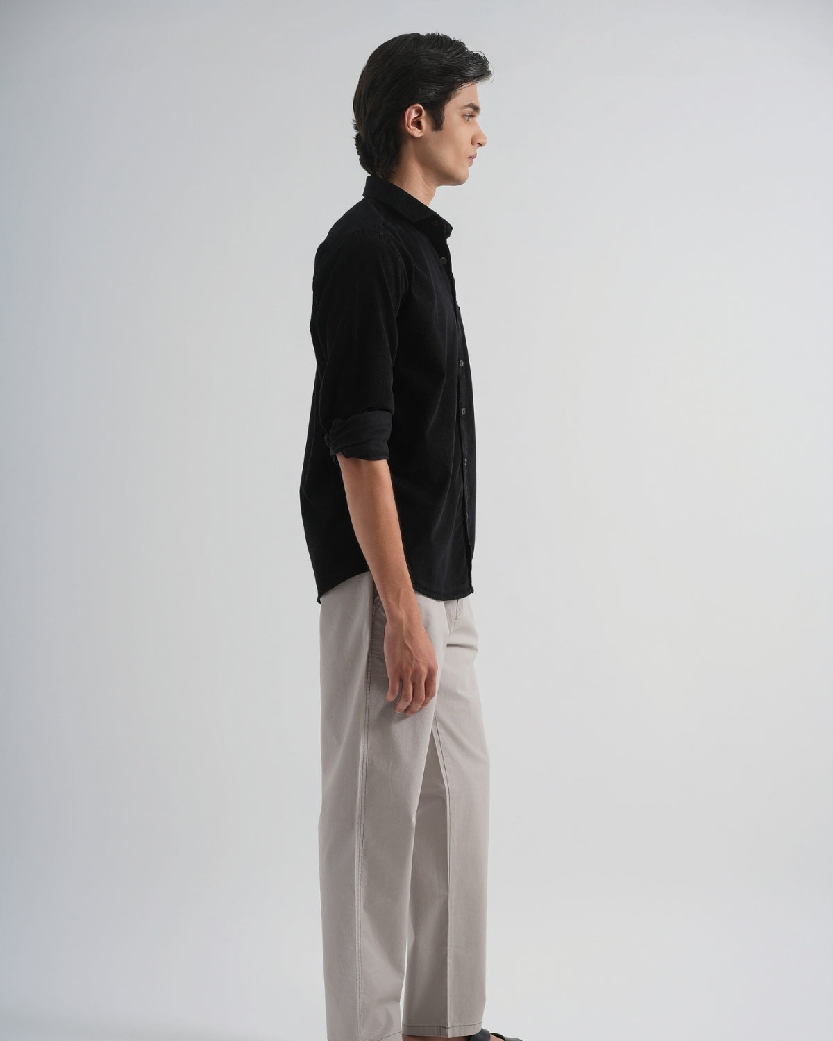 Man wearing a black shirt and beige pants on a white background