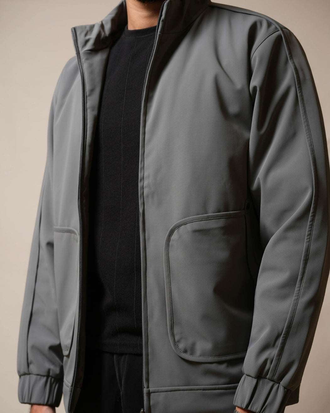 Gray jacket worn by a person on a beige background