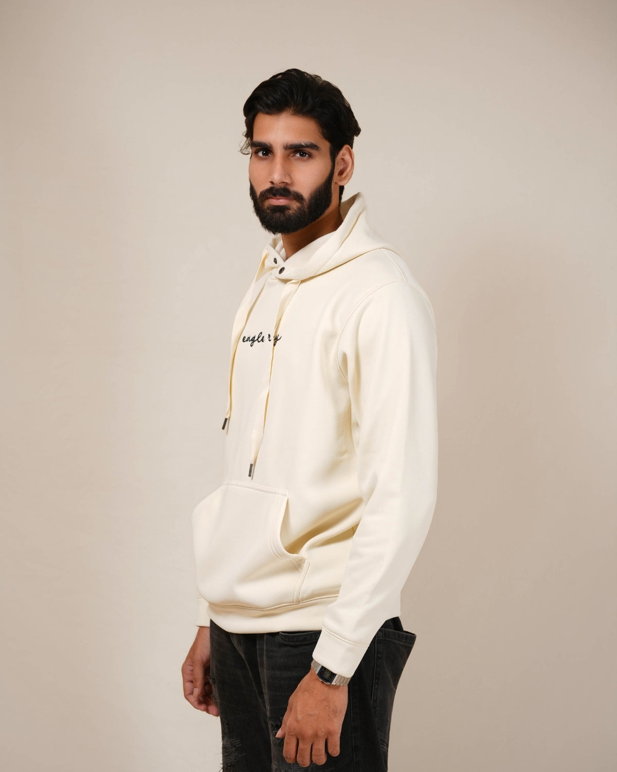 Man wearing a white hoodie with a brand logo on a plain background