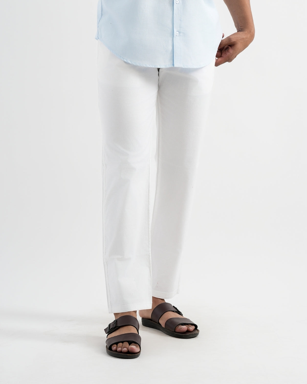 Person wearing white pants and brown sandals on a white background